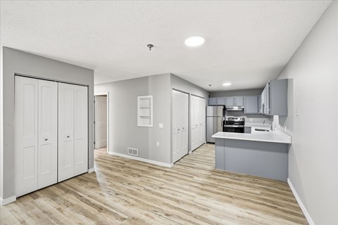 A kitchen with white cabinets and a wooden floor.